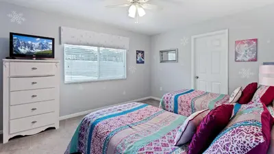 a bedroom with two beds and a tv and a dresser at 2644 Daulby in Kissimmee