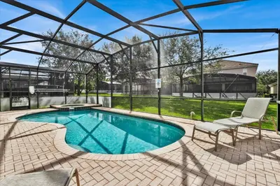 a swimming pool with a pergola and a chair next to it at 7756 Grassendale in Kissimmee