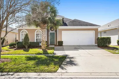 a house with a palm tree and a white garage at 8157 Fan Palm in Kissimmee