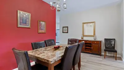 a dining room with a red wall and a table and chairs at 8159 Fan Palm in Kissimmee