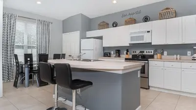 a kitchen with white cabinets and a table and chairs at 8208 Fan Palm in Kissimmee