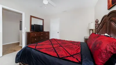 a bedroom with a bed with a red comforter and a television at 8008 King Palm in Kissimmee