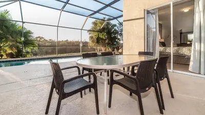 a table and chairs on a patio with a pool at 8135 Sun Palm in Kissimmee