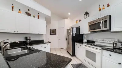 a kitchen with white cabinets and black counter tops at 8136 Sun Palm in Kissimmee