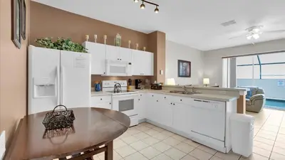 a kitchen with white cabinets and a wooden table at 2326 Silver Palm in Kissimmee