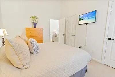 a white bedroom with a bed and a tv on the wall at 2209 Wyndham Palms in Kissimmee