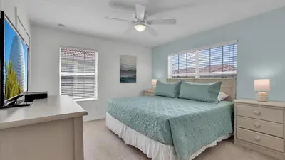 a bedroom with a bed and a desk and windows at 8967 Cat Palm in Kissimmee