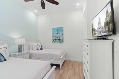 a white bedroom with two beds and a flat screen tv at 8000 Lost Shaker Lane in Orlando