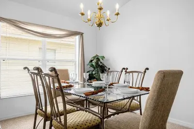 a dining room table with chairs and a chandelier at 201 Hideaway beach 4 beds - pool&spa in Kissimmee