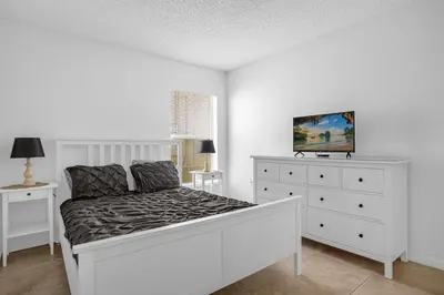 a white bedroom with a bed and a dresser at 201 Hideaway beach 4 beds - pool&spa in Kissimmee