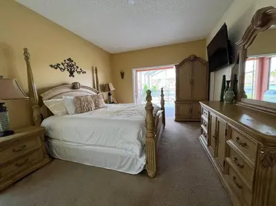 a bedroom with a bed and a dresser and a television at Villa Madiera 6 bedroom huge house in Kissimmee