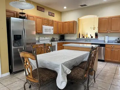 a kitchen with a table and a stainless steel refrigerator at Villa Madiera 6 bedroom huge house in Kissimmee