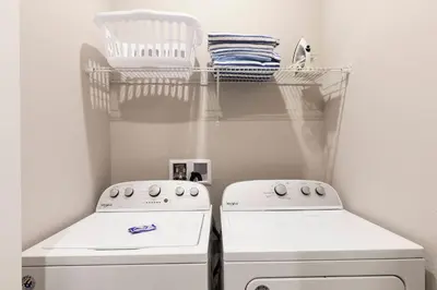 a laundry room with two white machines and a shelf at Gorgeous Dream Villa 5 min to Disney in Orlando