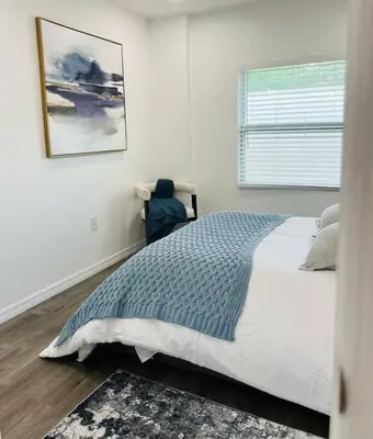 a white bedroom with a bed and a window at Roy's guest house in Orlando