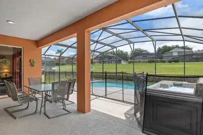 a screened in patio with a table and a tub at Be-Our-Guest Home! 15 mins to Disney! in Kissimmee