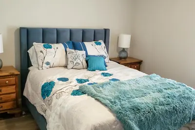a bed with a blue headboard and a blanket on it at Sanford Country Escape Fire Pit, Yard and Wildlife! in Sanford