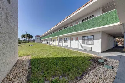 a building with a green roof and a grass yard at Travel Lodge by Wyndham 10 min from Disney in Kissimmee