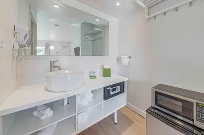 a white bathroom with a sink and a mirror at Travel Lodge by Wyndham 10 min from Disney in Kissimmee