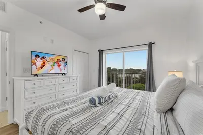 a white bedroom with a bed and a tv at 2BR condo minutes to Disney Springs in Orlando