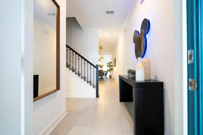 a hallway with a staircase with a black dresser and a mirror at 2681 Stunning home perfect for your family in Kissimmee