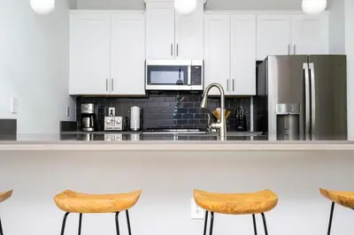 a kitchen with white cabinets and a counter with stools at Luxurious Home w Theme Beds & Private Pool in Kissimmee