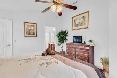 a bedroom with a bed with a ceiling fan and a dresser at 4 bedrooms pool home with water view and short drive from Disney in Kissimmee