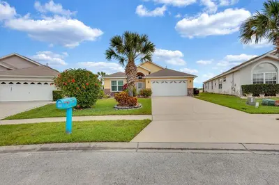a house with a blue mailbox in front of a driveway at 4 bedrooms pool home with water view and short drive from Disney in Kissimmee