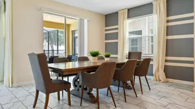 a dining room with a wooden table and chairs at Storey Lake 6BR Cozy Home Private Pool Near Disney in Kissimmee