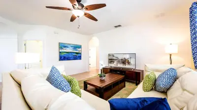 a living room with a white couch and a ceiling fan at 6BR Private Pool, Spa, Gameroom, Close to Disney in Orlando
