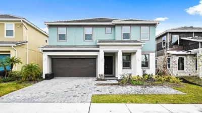a blue house with a garage in a yard at Opulent Retreat, Pool & Lake View, Near Parks in Kissimmee