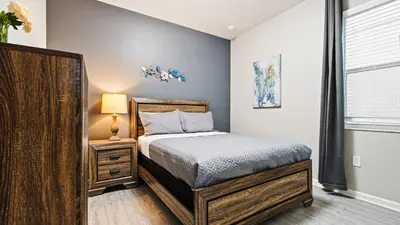 a bedroom with a bed and a lamp and a window at Opulent Retreat, Pool & Lake View, Near Parks in Kissimmee