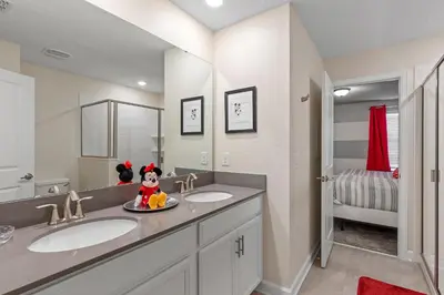 a bathroom with two sinks and a large mirror at Family Reunion 10BR Villa Pool/SPA Near Disney! in Kissimmee