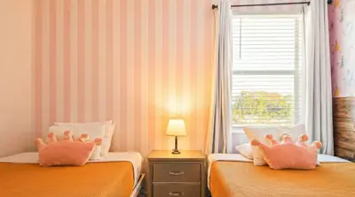 a bedroom with two beds with pink pillows on them at Spacious 12-Bed Villa with Pool & Resort Amenities in Kissimmee
