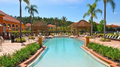 a swimming pool at a resort with palm trees at Lakeview Spacious 12br Themed Home Game/Pool/Spa in Kissimmee