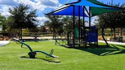 a park with a playground with an umbrella and a swing set at Lakeview Spacious 12br Themed Home Game/Pool/Spa in Kissimmee