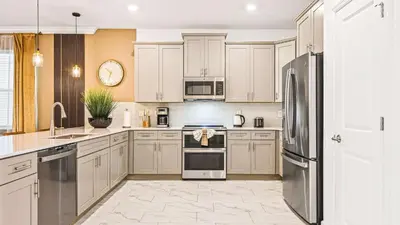 a kitchen with white cabinets and stainless steel appliances at Lakeview 10BR Home Pool/SPA Game Room Disney Theme in Kissimmee