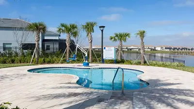 a swimming pool with palm trees and a swing at Lakeview 10BR Home Pool/SPA Game Room Disney Theme in Kissimmee
