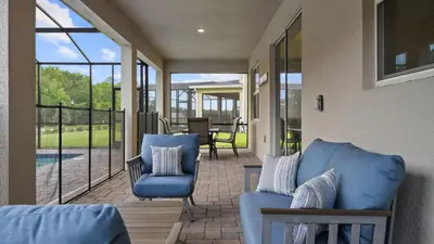 a porch with two blue chairs and a pool at Star Wars Disney Themed 10BR Villa Pool/Spa/Game in Kissimmee