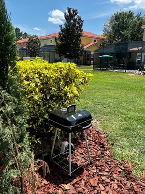a bbq grill sitting in the grass in a yard at Stylish 3 bd townhouse near Disney with private pool. in Kissimmee