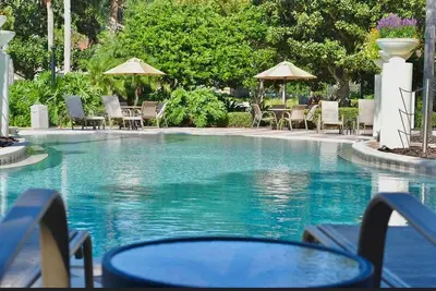 a swimming pool with chairs and tables and umbrellas at Stylish 3 bd townhouse near Disney with private pool. in Kissimmee