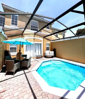a swimming pool with a table and an umbrella at Stylish 3 bd townhouse near Disney with private pool. in Kissimmee