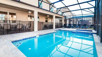 a large swimming pool with chairs and a table at Family Oasis: Pool, Themed Rooms & Resort Access in Kissimmee