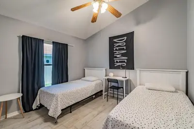 a bedroom with two beds and a table and a window at Santee Villa in Kissimmee