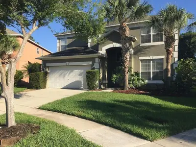 a house with palm trees and a garage at Emerald Escape in Kissimmee