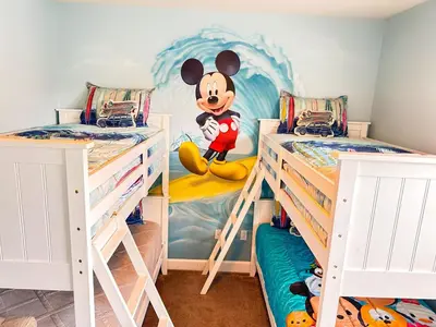 a bedroom with two bunk beds with mickey mouse mural at 3 bedrooms pool home Retreat Close to Disney in Orlando