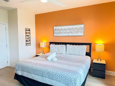 a bedroom with a large bed with an orange wall at Affordable Disney pool home 3 Bed 3 bath in Orlando