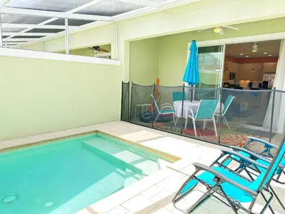 a swimming pool with two chairs and an umbrella at Affordable Disney pool home 3 Bed 3 bath in Orlando