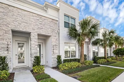 a white brick house with palm trees at 3 bedrooms pool home Hidden Forest Resort Amenities in Orlando