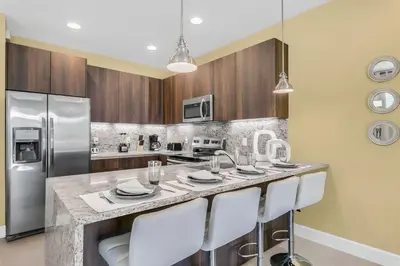 a kitchen with a large counter with white chairs at 3 bedrooms pool home with clubhouse amenities Retreat in Orlando