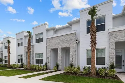 a white building with palm trees in front of it at 3 bedrooms pool home Hidden Forest Resort Amenities in Orlando
